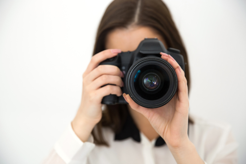 Woman photographer with camera over gray background